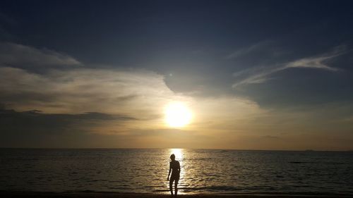 Silhouette man on beach against sky during sunset