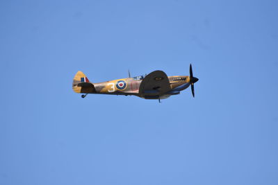 Low angle view of airplane flying against clear blue sky