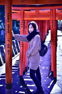 Full length portrait of woman standing at torii