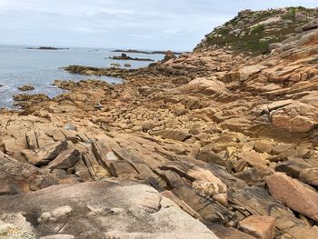 Rock formation on beach against sky