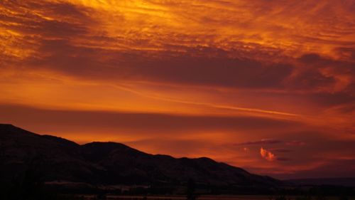 Scenic view of silhouette mountains against orange sky