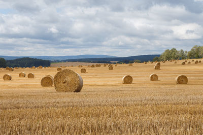 Hay bales on field against sky