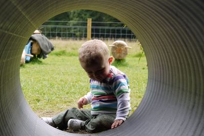 Full length of boy sitting by tunnel at park