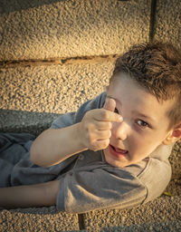 High angle portrait of boy gesturing while sitting on steps