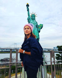 Woman looking away while standing against statue of liberty