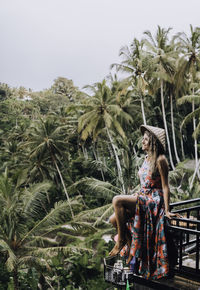 Woman standing by palm trees against sky