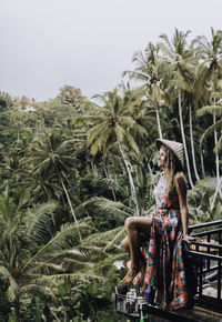 Woman standing by palm trees against sky