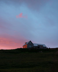 House on field against sky during sunset