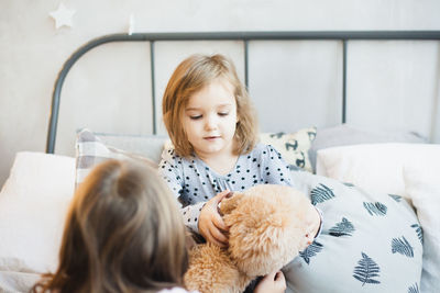 Mother and girl with toy on bed