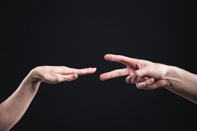 Close-up of hand holding hands over black background