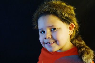 Portrait of cute boy smiling against black background