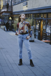 Full length of woman standing on footpath