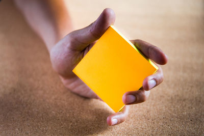 Close-up of hand holding yellow paper