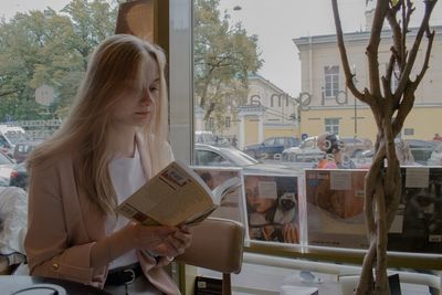 Portrait of woman sitting in glass window