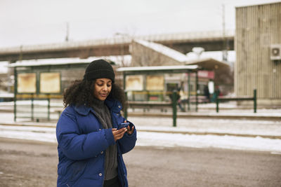Woman using phone at bus stop