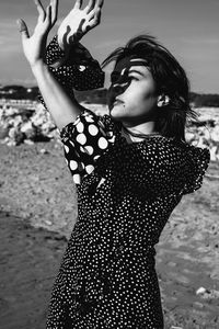 Young woman looking away while standing on beach