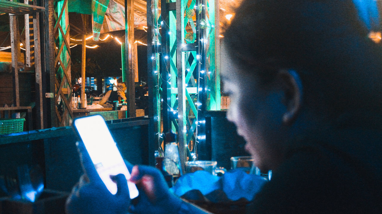 REAR VIEW OF WOMAN PHOTOGRAPHING THROUGH GLASS WINDOW