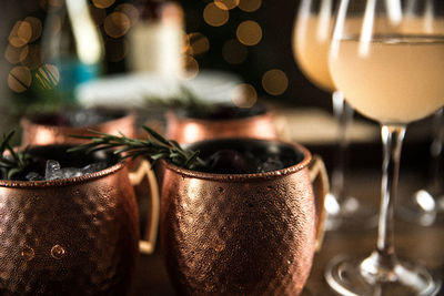 Copper mugs with rosemary sprigs and wine glasses arranged for celebration during the holidays 