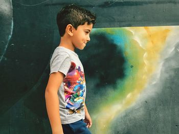 Side view of cute boy walking against wall