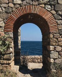 Stone wall by sea against sky