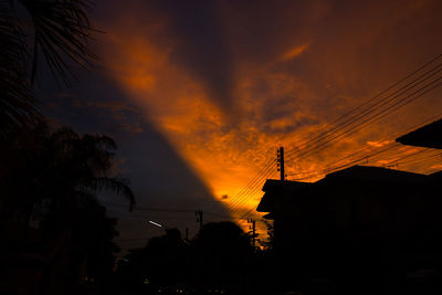 Low angle view of silhouette trees and buildings against sky during sunset