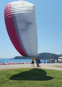 People enjoying at beach against clear sky