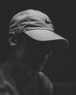 Close-up portrait of man wearing hat against black background