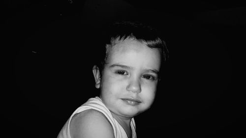 Portrait of cute boy against black background