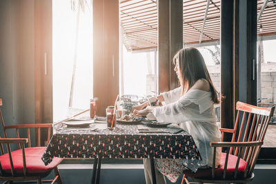 Side view of woman sitting on table