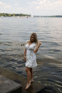 Full length portrait of a smiling young woman standing in water