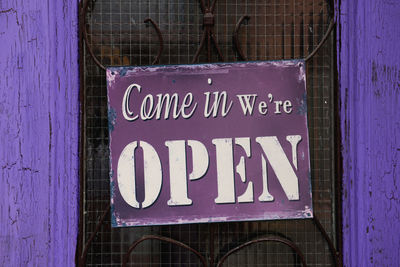 Open sign hanging on purple door