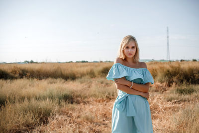 Portrait of teenage girl wearing dress standing on land against sky