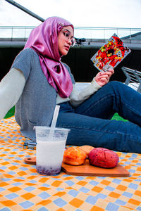 Midsection of woman with drink sitting on table