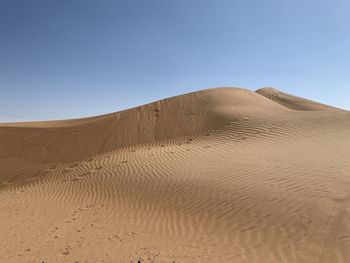 Sand dunes in desert against clear sky