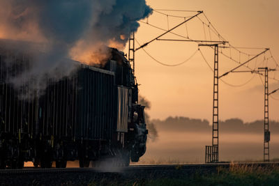 Train on railroad track against sky during sunset