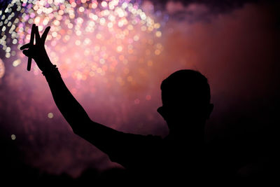 Silhouette of a head, a arm and fingers of a man in front of firework explosion