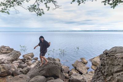 Full length of woman standing on rocky shore