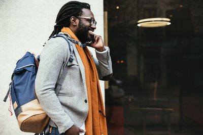 Smiling man talking on mobile phone while walking in city