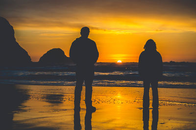 Silhouette of people on beach at sunset