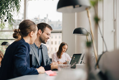 Creative professionals discussing over laptop at desk in coworking space