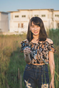 Portrait of smiling young woman standing on field