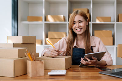 Portrait of young woman using laptop at desk in office