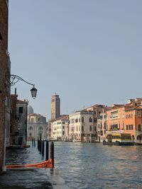 Canal amidst buildings against clear sky