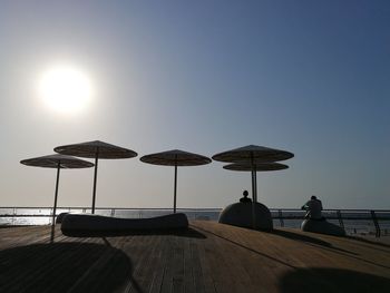 People relaxing at beach against clear sky