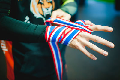 Midsection of man tying ribbon on hand