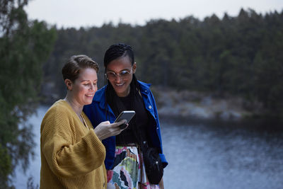 Smiling female couple using smart phone outdoors