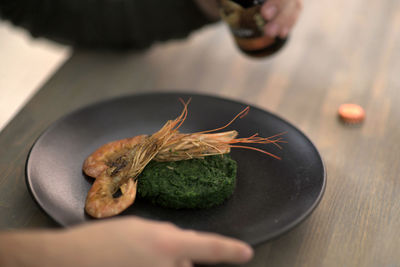 Cropped image of person preparing food in plate