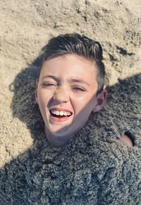 Boy buried in sand fun at the beach 