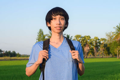 Portrait of teenage girl standing on field against sky