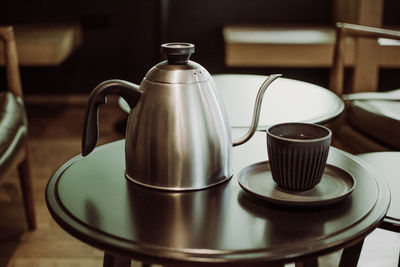 Close-up of coffee cup and kettle on table at home